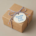 Texas Toy Lab gift card, shown as a wrapped gift box (delivered by email, not a physical box)